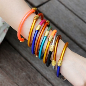 Pulseras de silicona coloridas con dijes dorados en relieve en la muñeca
