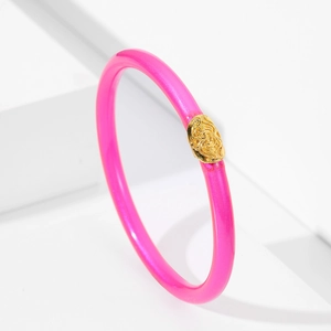 Detalle de pulsera de silicona rosa vibrante con decoración de metal dorado en relieve