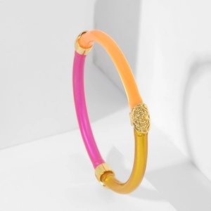 Détail d'un bracelet en résine tricolore avec une breloque florale dorée gravée en relief