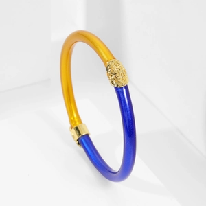 Detalle de pulsera de silicona azul y dorado con relieve metálico de cabeza de león