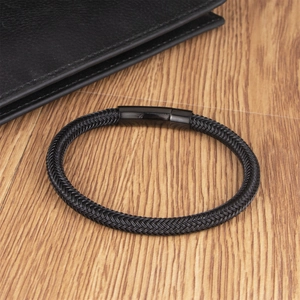 Men's black braided stainless steel cable bracelet with magnetic clasp on wood surface