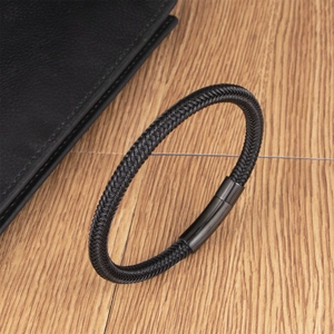 Men's black braided wire bracelet with magnetic steel clasp on a wooden surface
