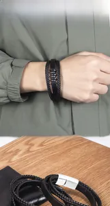 Detail of multi-layer black leather bracelet with metal rings and magnetic silver clasp