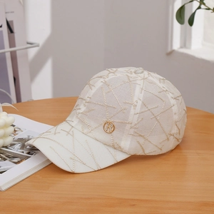 White baseball cap with gold embroidery and a metallic R logo on a wooden table