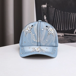 Close-up of sparkling rhinestone star pattern and white flower on light blue denim baseball cap