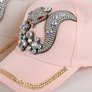Close-up of pink baseball cap featuring a rhinestone squirrel and crystal brim details