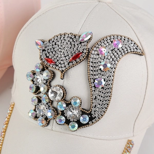 Close-up of rhinestone fox embroidery on a beige cotton baseball cap with floral sequins
