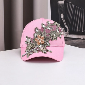 Détail d'une casquette rose avec broderies florales en 3D et strass brillants incrustés
