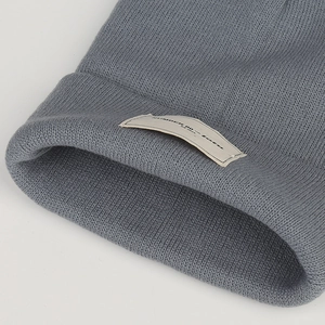 Close-up of dark grey knitted beanie showing thick ribbed texture and lofu fabric label