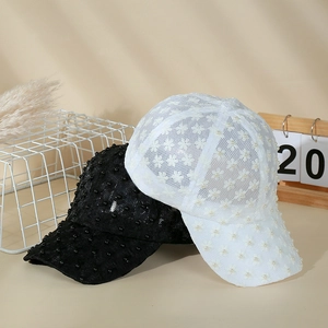 Detail of lace baseball caps with floral textures and white pearl embellishments