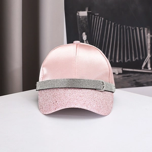 Detailed view of pink satin baseball cap with sequined brim and rhinestone buckle decoration