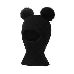 Detail of black winter balaclava with dual fur pom-poms and ribbed knit texture