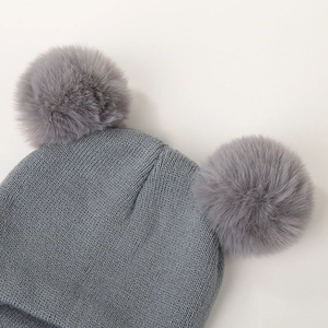 Detail view of the fine knit texture and soft faux fur double pom-pom on the gray baby hat