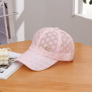 Detail of light pink floral lace baseball cap featuring a golden diamond M logo