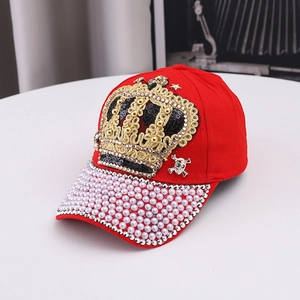 Détail de la casquette rouge avec couronne en paillettes, bord perlé et tête de mort