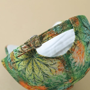 Detailed view of the adjustable silver metal buckle and floral leaf pattern on baseball cap