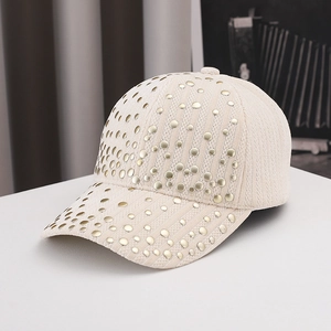 Dettaglio ravvicinato del cappellino in velluto crema con borchie dorate decorative