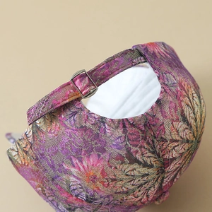 Detail of adjustable metal buckle and colorful floral lace fabric on baseball cap