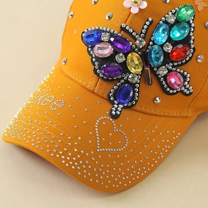 Detail of colorful gemstone butterfly and silver rhinestones on a yellow baseball cap