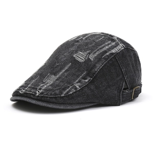 Close-up of side view of black denim beret hat with vintage distressed hole design