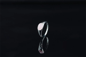 Dettaglio di una pietra preziosa rosa ovale incastonata in un anello sigillo in argento lucido
