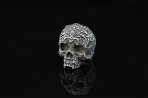 Detailed macro view of vintage gothic skull ring with ornate floral carvings and reflection