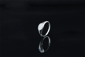 Macro di un anello a sigillo in argento con gemma ovale su fondo nero riflettente