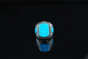 Detail of vintage turquoise ring with intricate ethnic engravings on a black surface