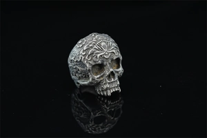 Macro shot of vintage skull ring featuring detailed floral engravings and a dark gray finish
