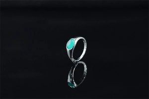 Dettaglio dell'anello in acciaio inossidabile argento con gemma ovale verde smeraldo e riflesso