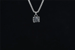 Macro detail of silver vintage suitcase pendant with Paris engraving on box chain