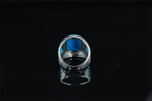 Detail view of vintage silver ring with turquoise stone and hollow pattern on black background
