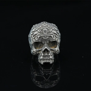 Vintage gothic skull ring with baroque engravings on black reflective surface
