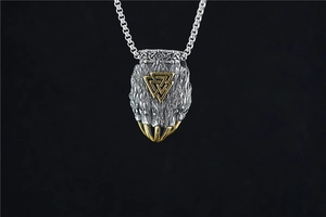 Macro detail of Viking bear paw pendant with golden Valknut symbol and silver box chain