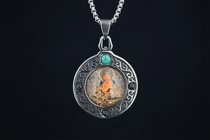 Macro detail of Buddhist Jambhala Thangka pendant with turquoise in vintage steel