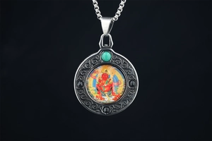 Macro shot of Thangka pendant with turquoise bead and detailed deity artwork on steel chain