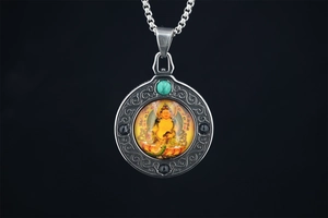 Detailed close-up of Buddhist Jambhala Thangka pendant with turquoise bead on black background