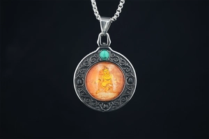 Macro shot of Buddhist mandala pendant with turquoise bead and engraved steel frame