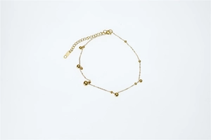 Détail d'un bracelet perlé en acier avec sphères dorées polies et fermoir mousqueton