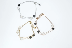 Detail of titanium steel layered bracelets in gold, silver, and rose gold with disc charms