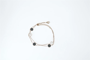 Detailed macro view of double-layer rose gold bracelet with black and white disc charms