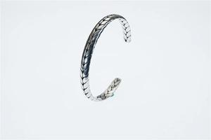 Dettaglio della trama a spiga vintage su un bracciale rigido aperto a forma di C