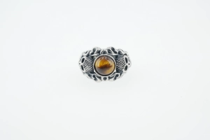 Détail d'une bague punk vintage avec pierre oeil de tigre polie et relief gothique
