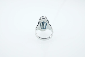 Close-up of gothic coffin ring with blue gemstone and retro floral engraved metal band