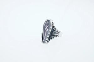 Macro detail of gothic vampire coffin ring with character relief and intricate vine patterns