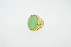 Gros plan d'une bague vintage dorée avec filigrane et pierre précieuse verte ovale