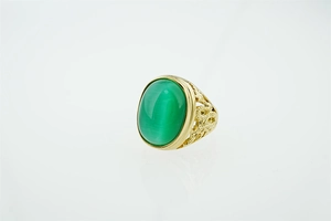 Gros plan détaillé d'une bague vintage en acier titane avec pierre verte et gravure dorée