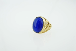 Détail de bague dorée vintage avec grande pierre œil-de-chat bleue et filigrane ciselé