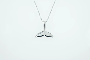 Detailopname van gepolijste walvisstaart hanger aan een zilveren titanium stalen ketting