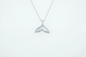 Detail van zilveren walvisstaart ketting met witte parelmoer inleg op een witte achtergrond